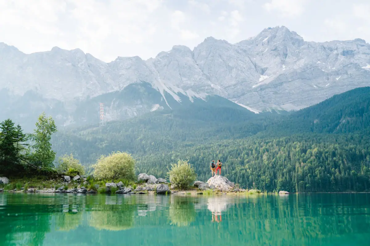 People standing on a rock in front of a lake.