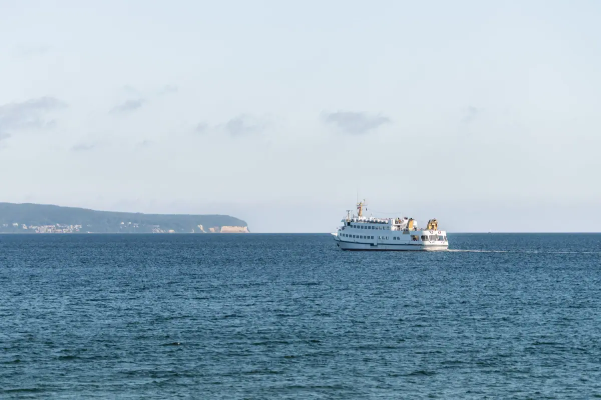 A boat on the water is heading towards the chalk cliffs on Rügen.