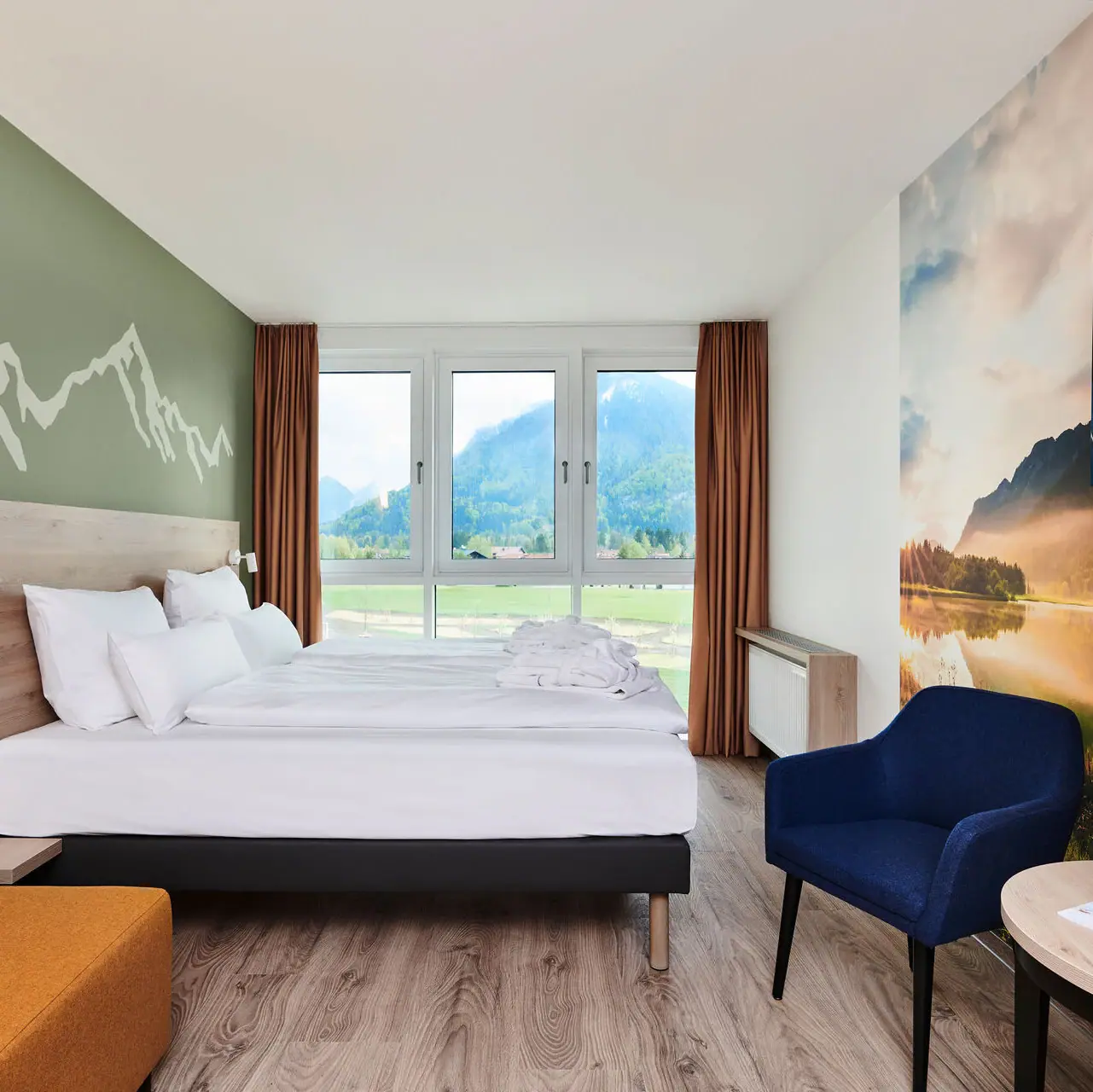 Rooms at the aja Ruhpolding A room with a bed and a view of the mountains from the window of the aja Ruhpolding.