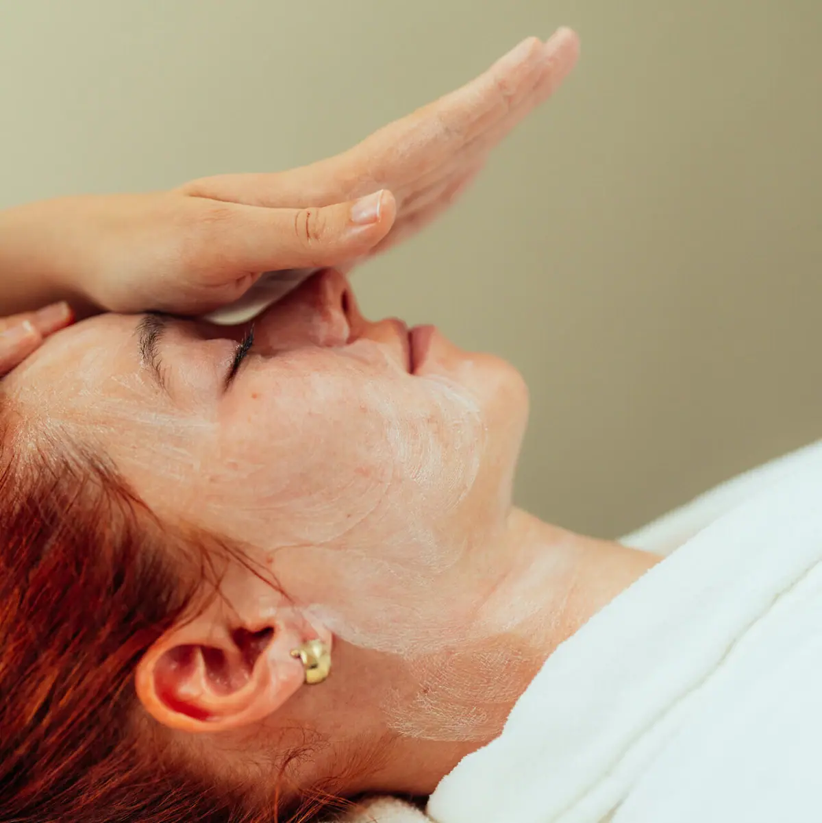 A woman is lying with her hand over her face.
