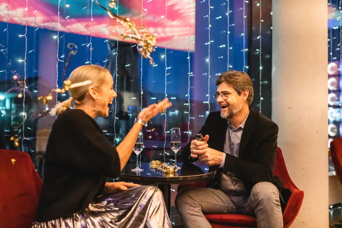 A man and a woman are sitting at a table with glasses of wine.