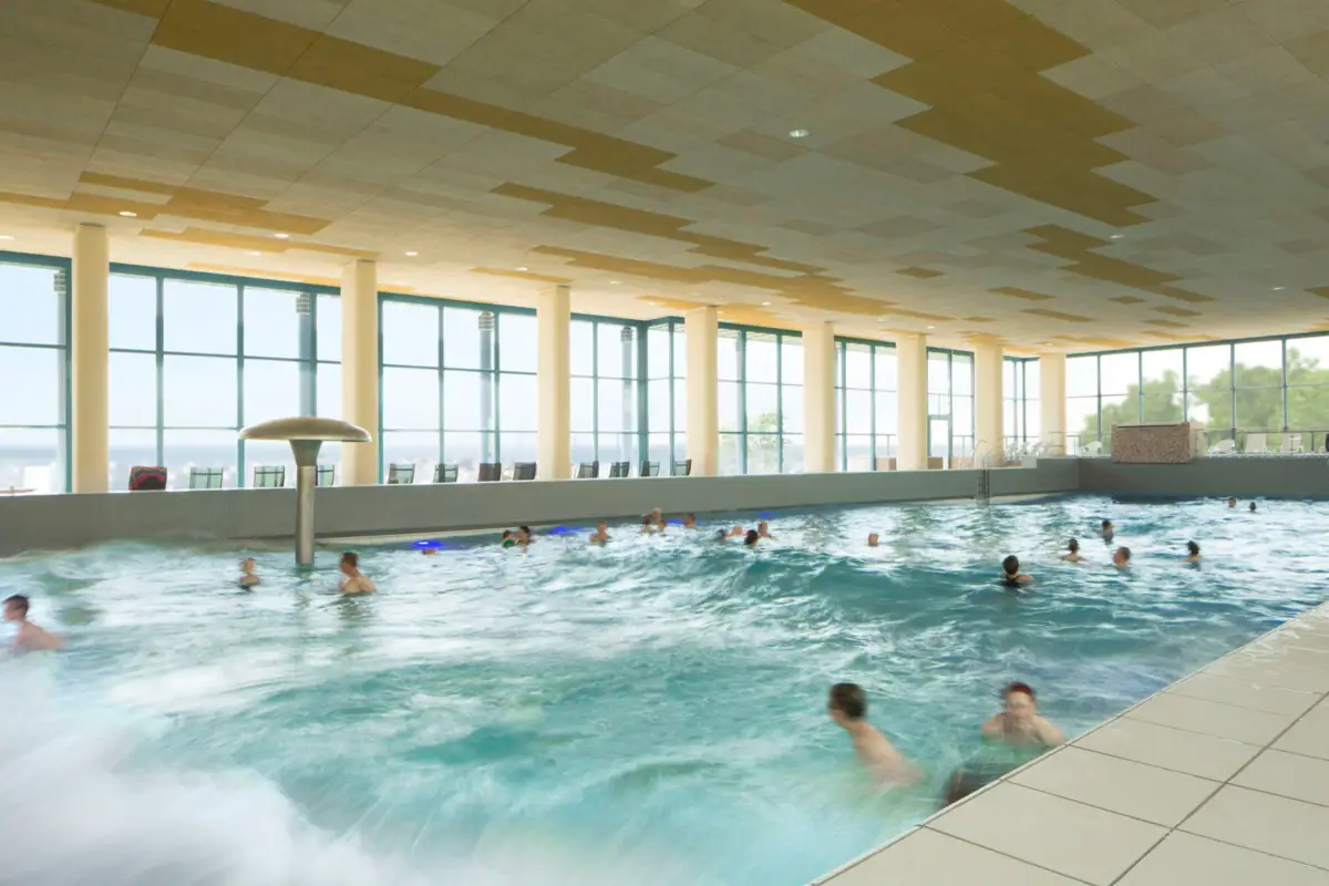 A large indoor swimming pool with people swimming in it.