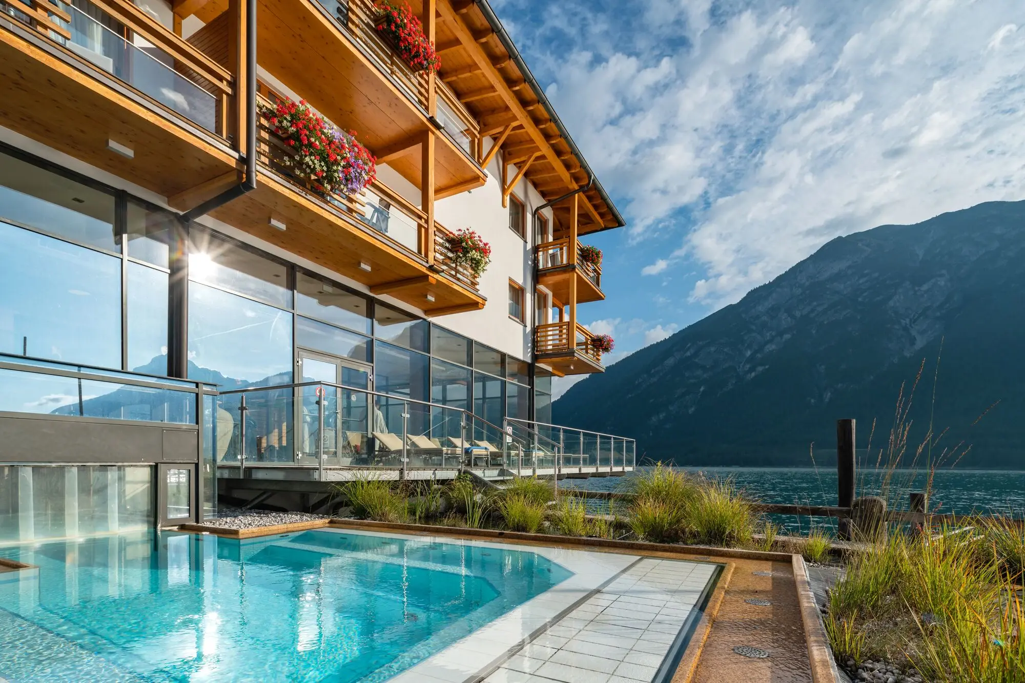 Swimming pool next to a building under a blue sky with mountains in the background.