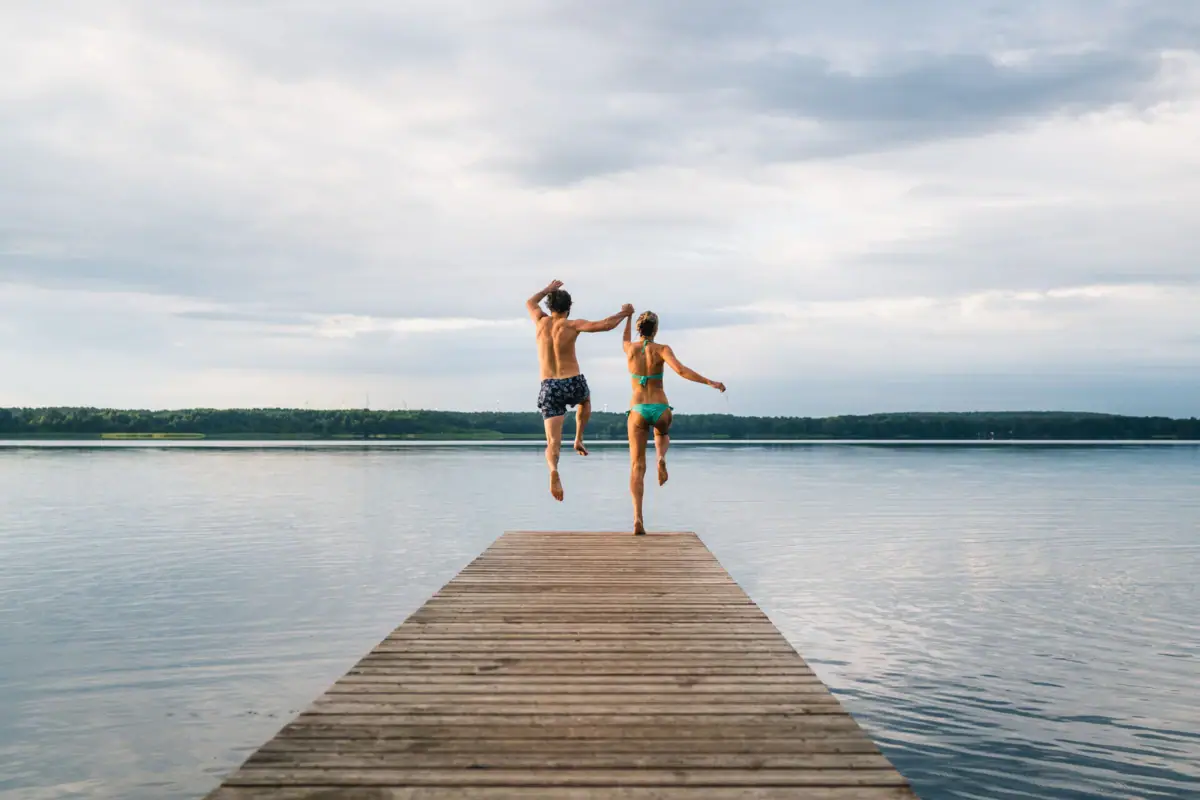 A man and a woman jump into the water.