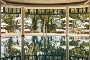 A swimming pool with parasols and chairs in the background.