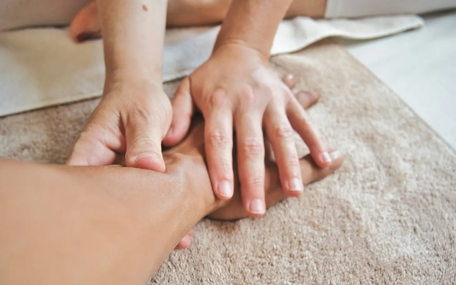 One hand and the arm are massaged by two other hands.