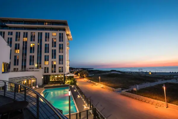 Wellness hotel aja Warnemünde The hotel with the outdoor pool and a walkway along the Baltic Sea.