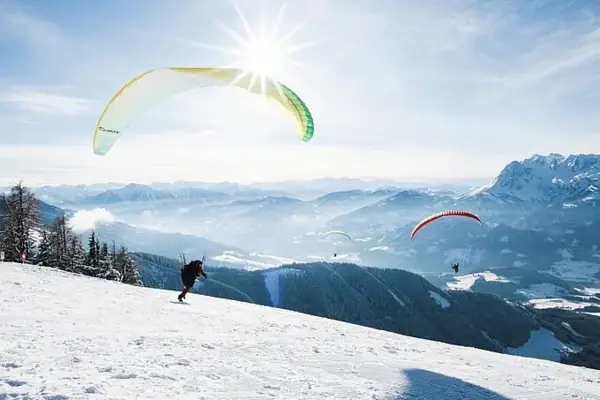 Group of people paragliding on a snowy mountain.