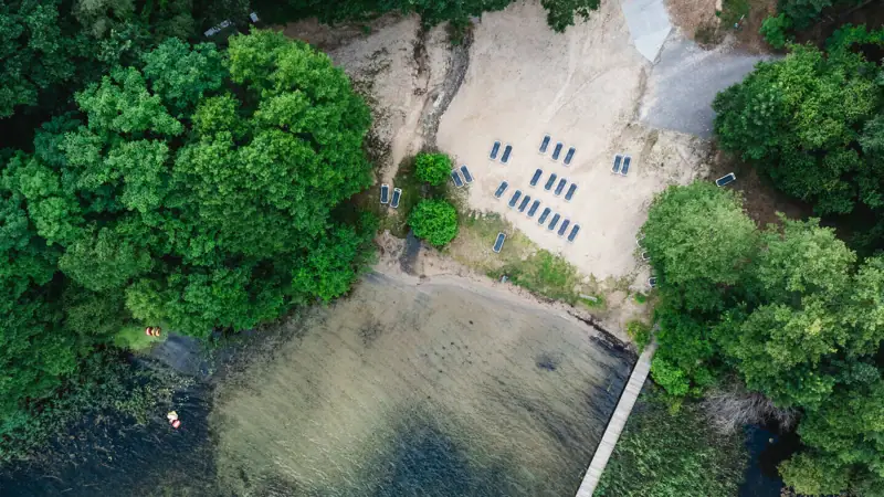 aja Bad Saarow A footbridge over a body of water with chairs and trees.