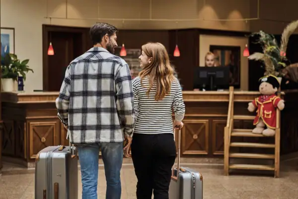 A man and a woman with luggage in the hotel lobby.