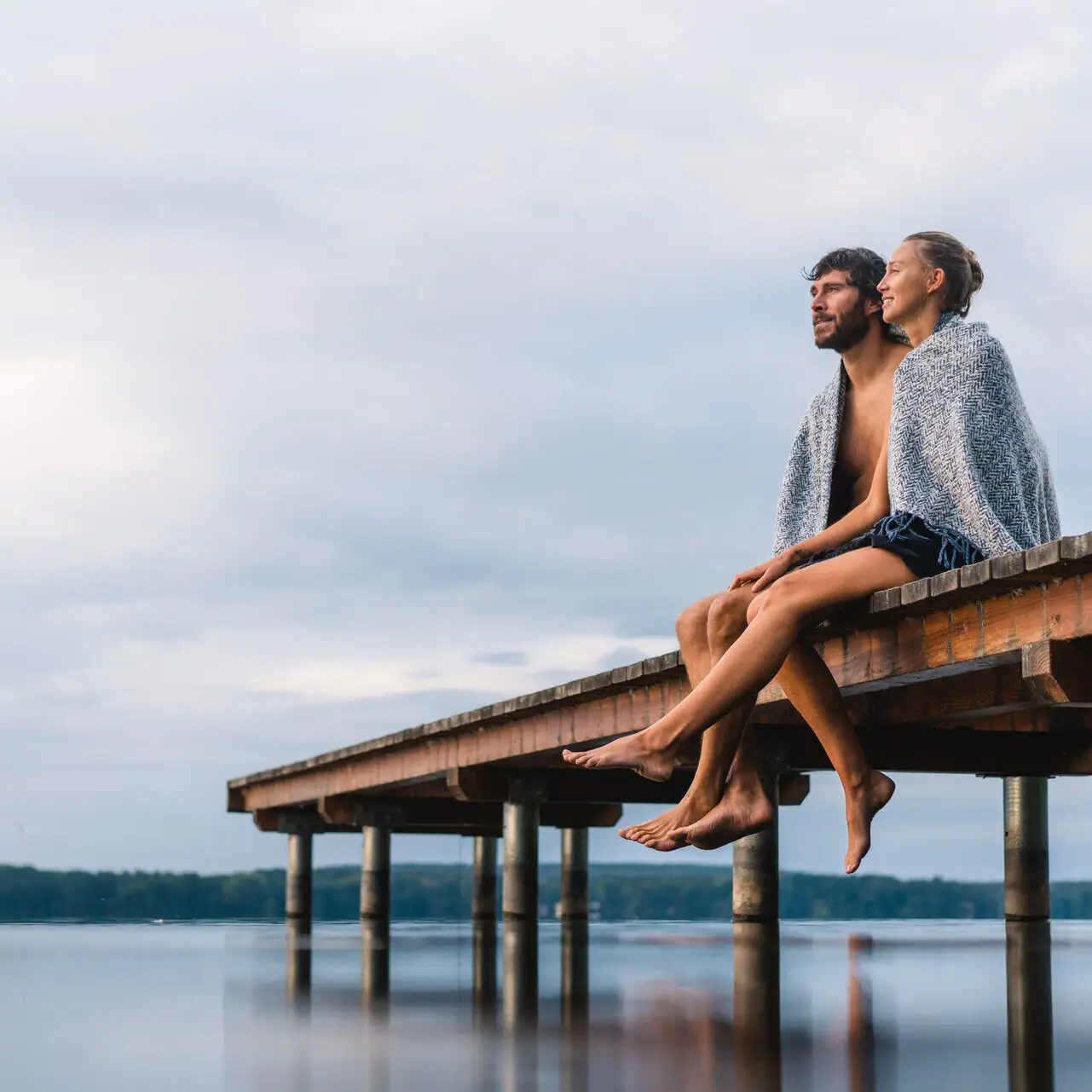 Experiences in Bad Saarow A man and a woman are sitting on a jetty by the lake.