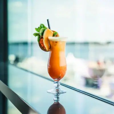A glass with a cocktail and citrus garnish on a table.