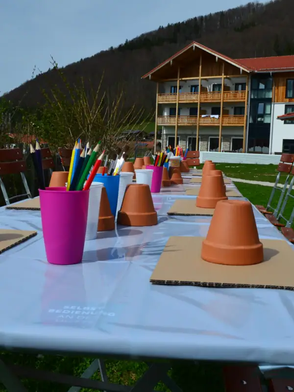 A table with a group of clay pots and pens on it.