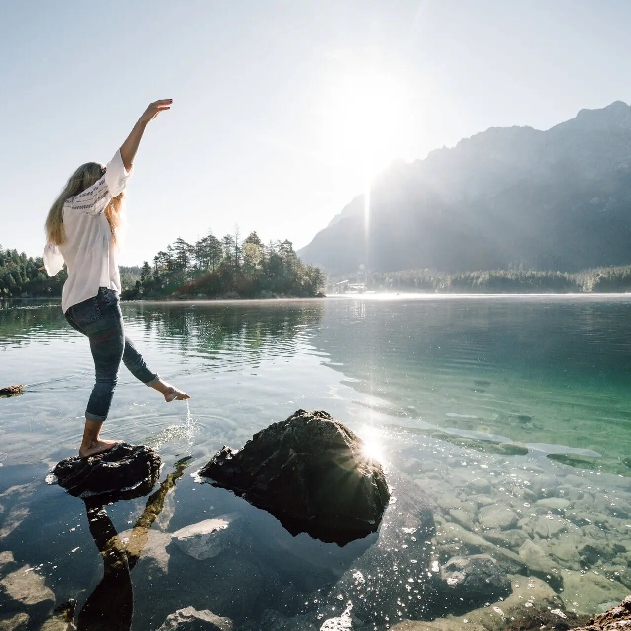 A woman balances on a stone at the Eibsee in Garmisch-Partenkirchen.