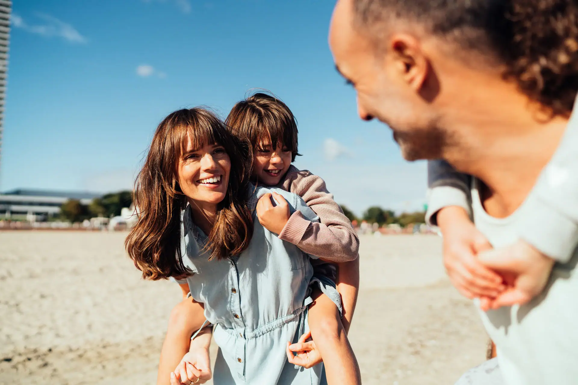 A man and a woman hold a child on the beach.
