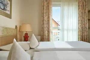 Double room landside A bed with white sheets and a lamp in a room with a window.