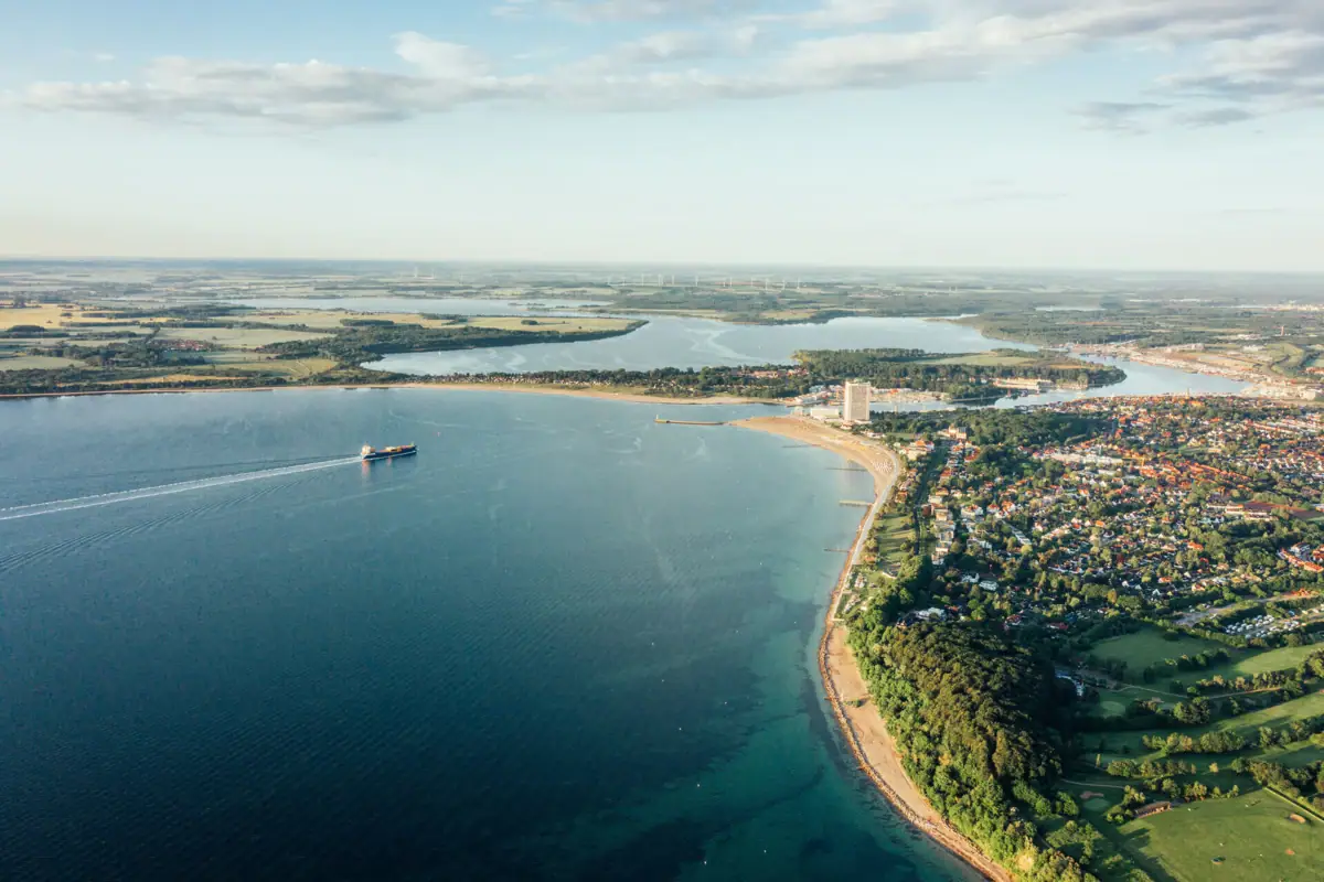 Aerial view of a body of water and a coastal town under a cloudy sky.