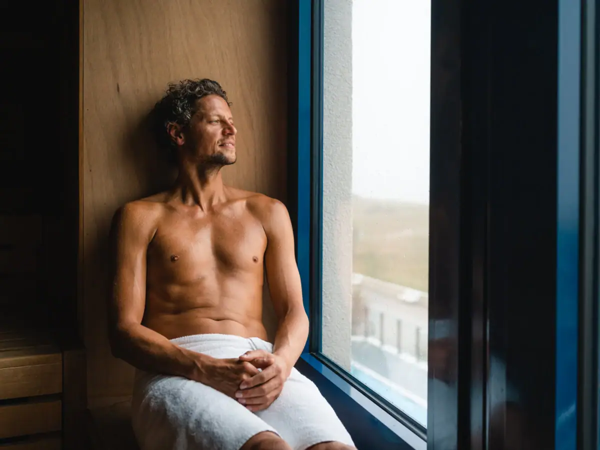 Sauna at aja Warnemünde A man sits on a windowsill in the sauna.
