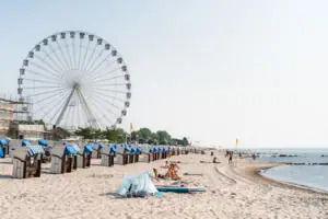 Strand mit Riesenrad und Menschen im Vordergrund.