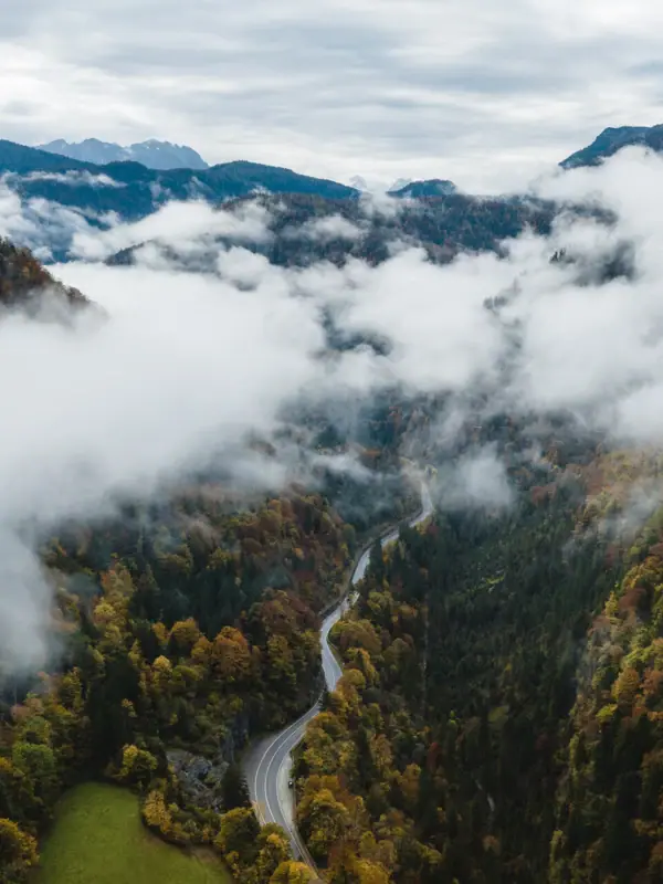 Ruhpolding Mountain Panorama A winding road through a valley filled with clouds.