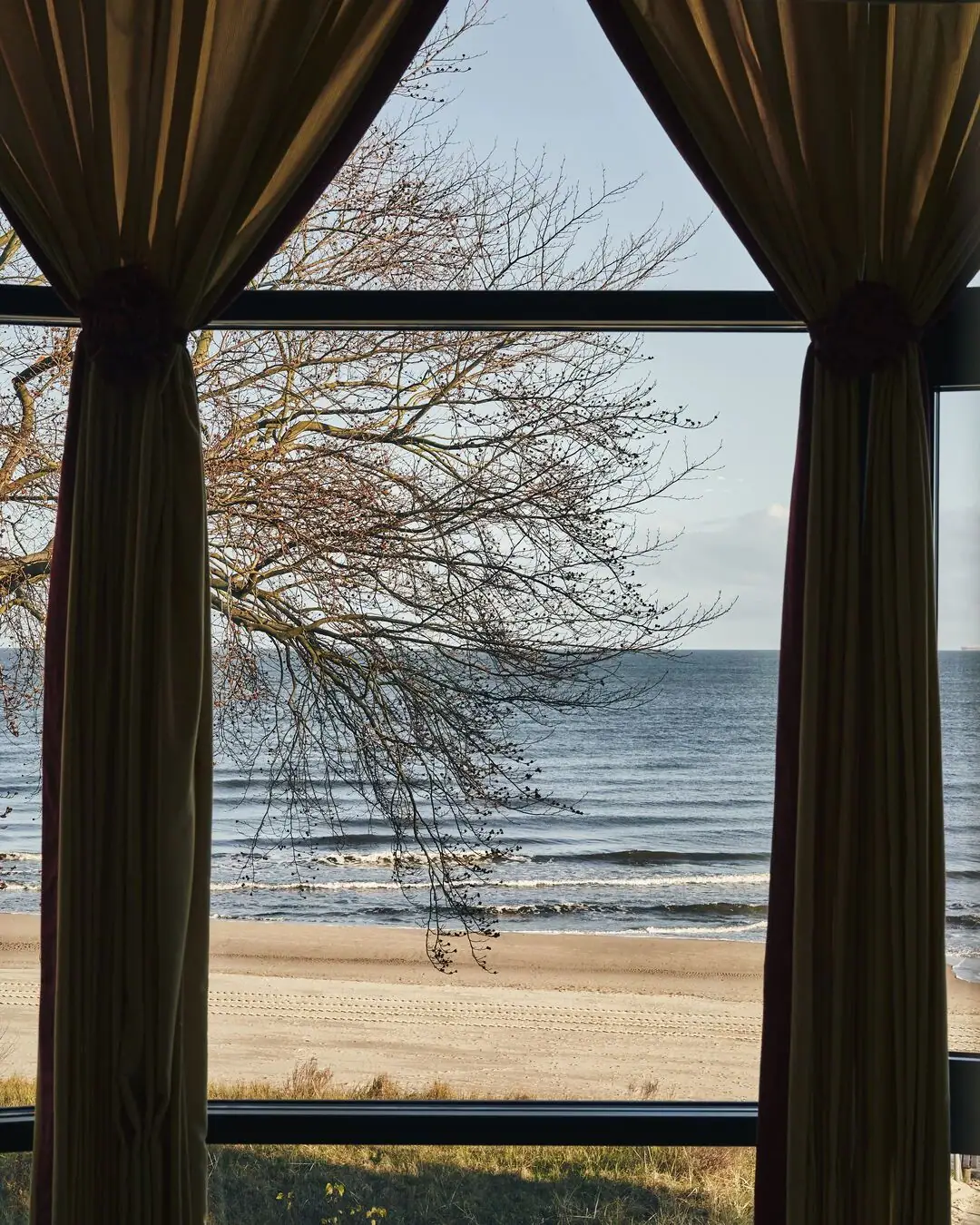 Fenster mit Vorhängen und Blick auf den Strand
