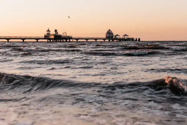 A stretch of water with a jetty and a building in the distance.