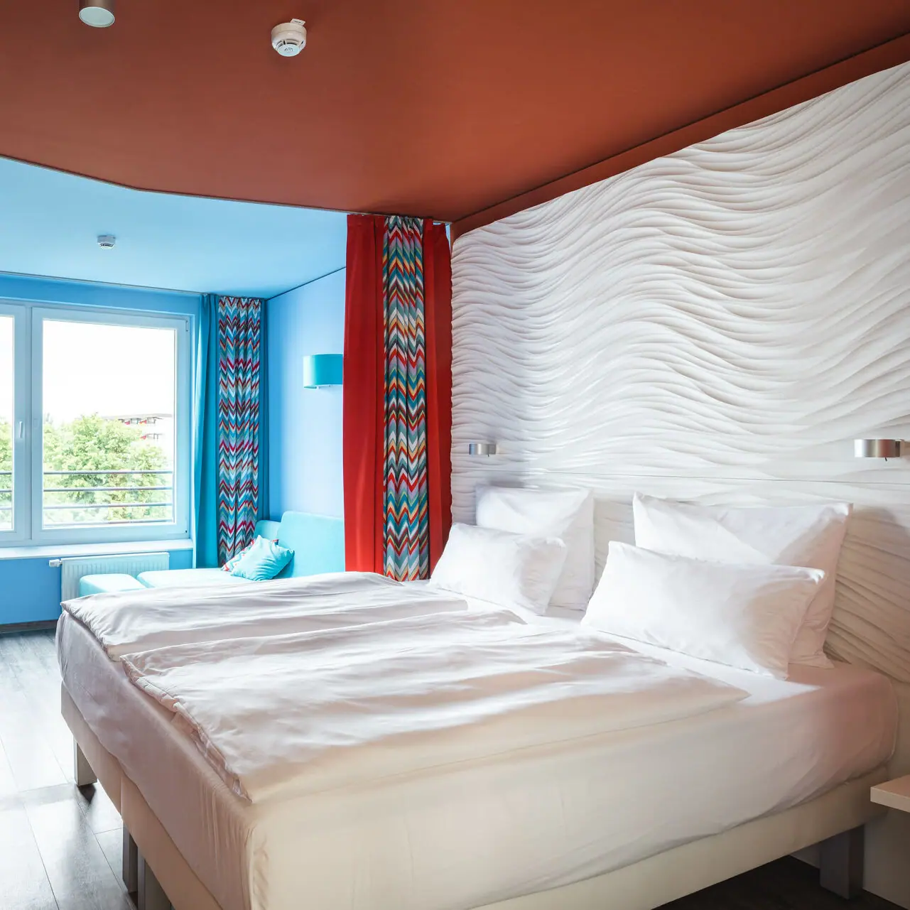 A hotel room with a large bed and red curtains.
