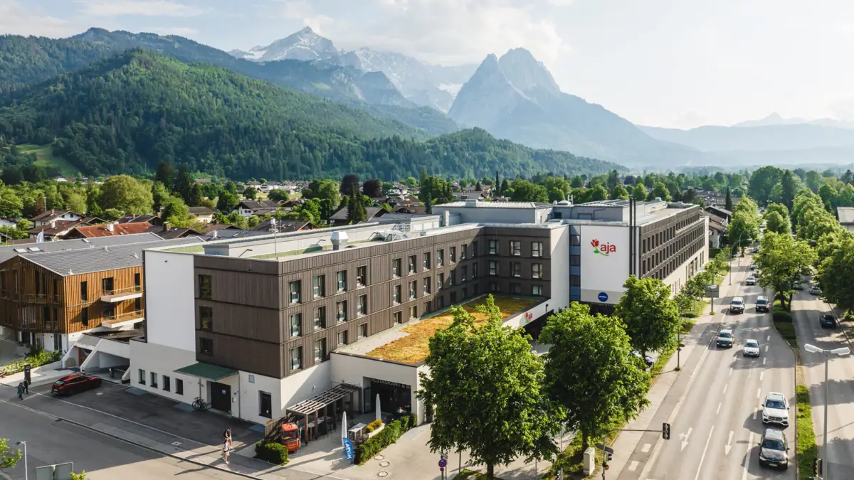 aja Garmisch-Partenkirchen A building with trees and mountains in the background.