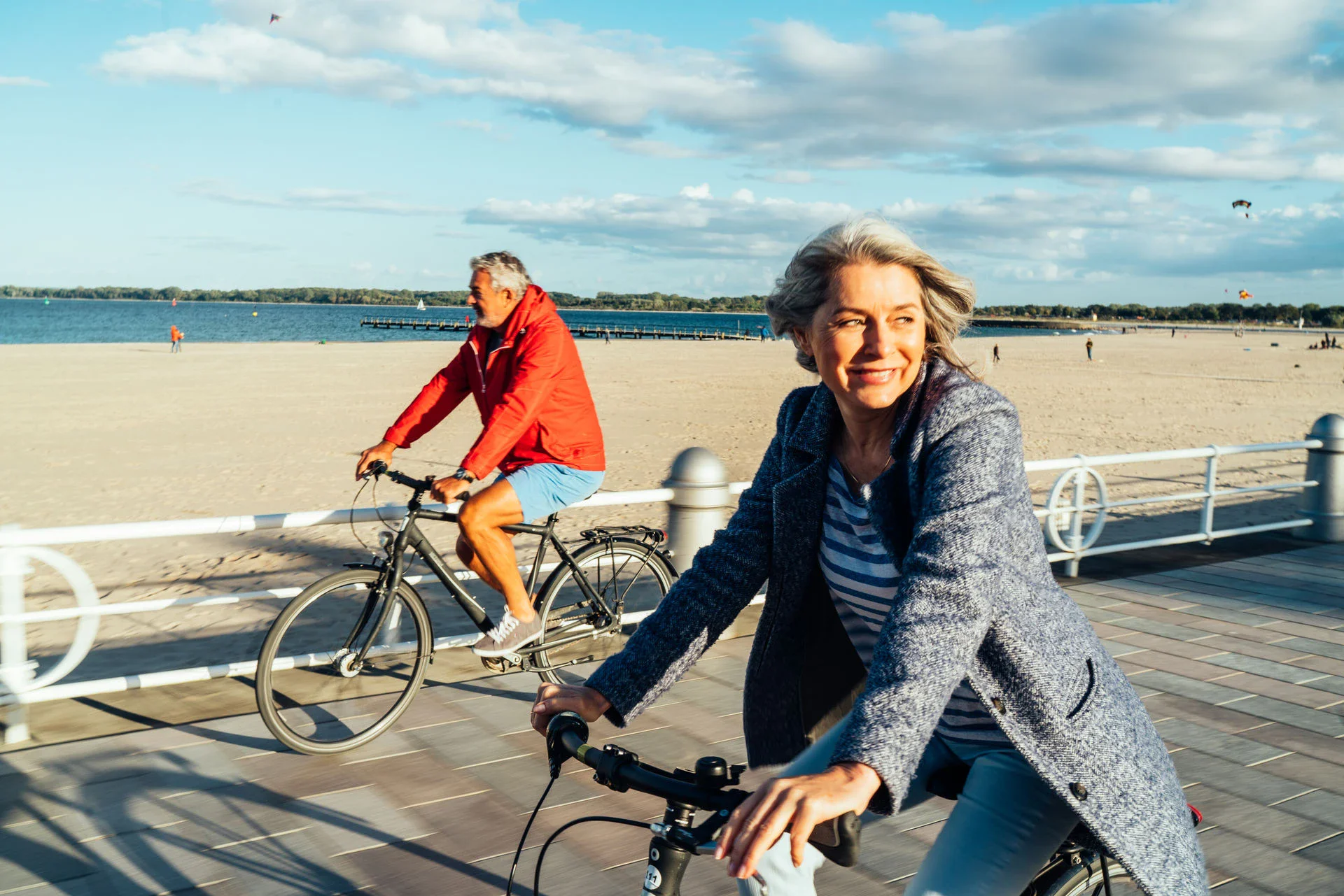 A man and a woman ride bicycles along a beach promenade