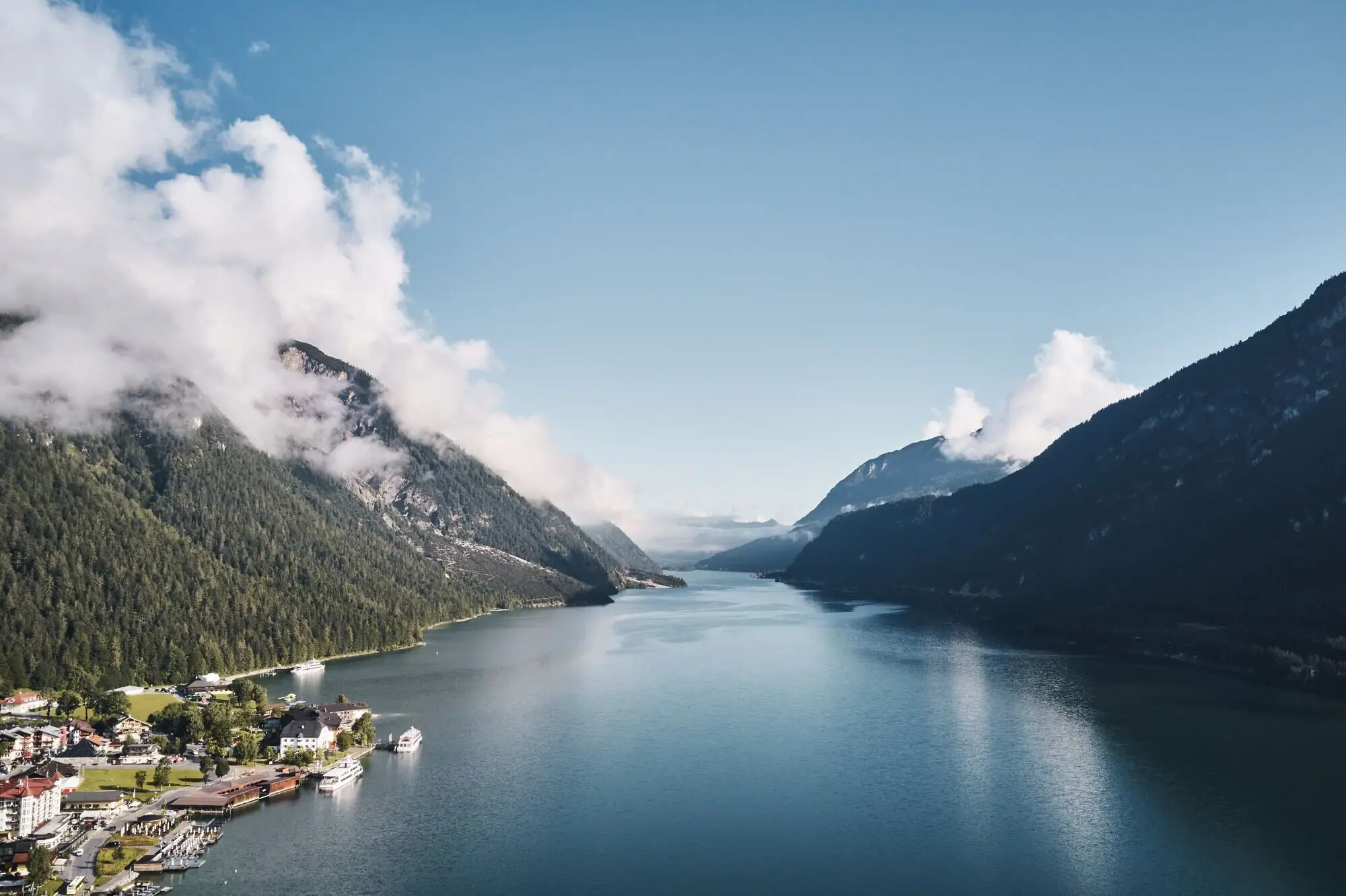 Lake Achensee A body of water with a house and mountains in the background.