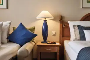 Lamp on a table next to a bed.