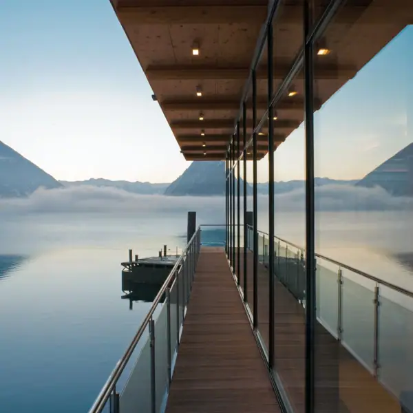 A terrace with glass walls and railings overlooking a body of water.