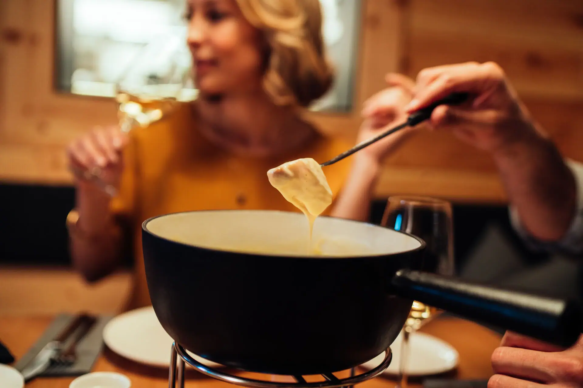 A person dips food into a pot.