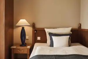 A bed with a lamp on a bedside table.