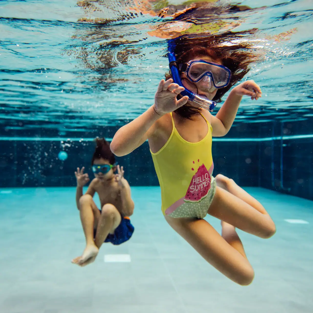 Children in the pool Two children swimming underwater in a swimming pool.