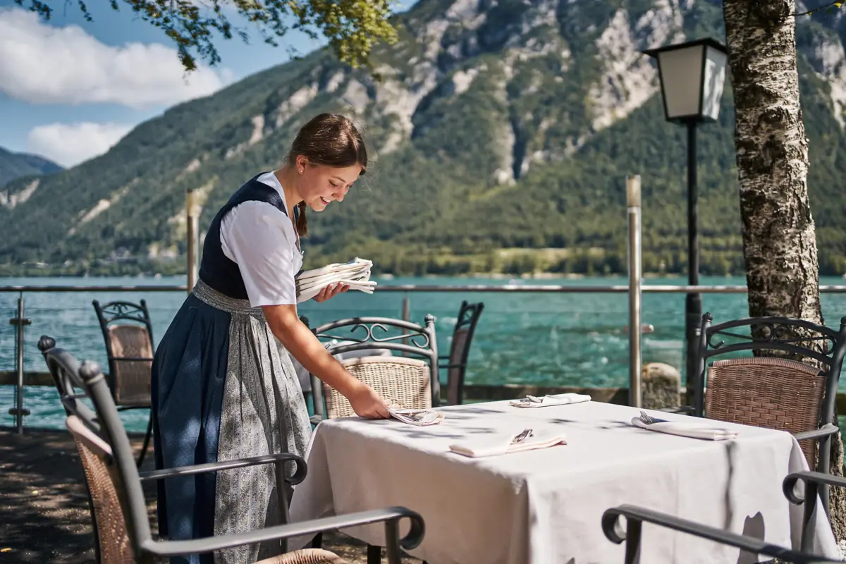 Outdoor area Achensee A woman in a dress standing at a table by the lake achensee.