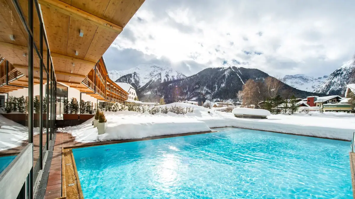A pool in the snow with mountains in the background.