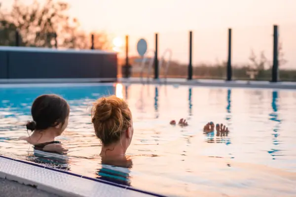 Outdoor pool Two women swimming in an outdoor pool at sunset.