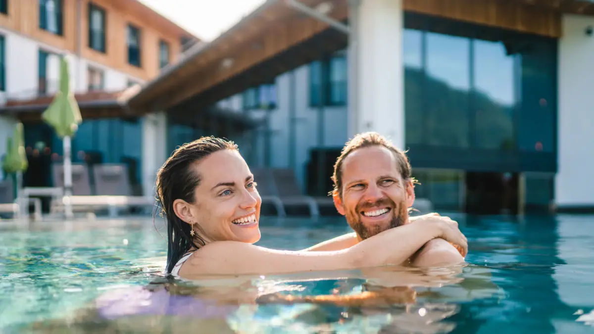 Outdoor pool at aja Ruhpolding A man and a woman smiling in a swimming pool.