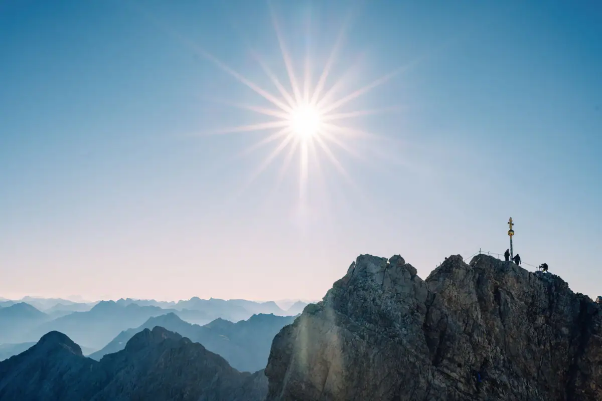 Sun shining over the Zugspitze with summit cross.