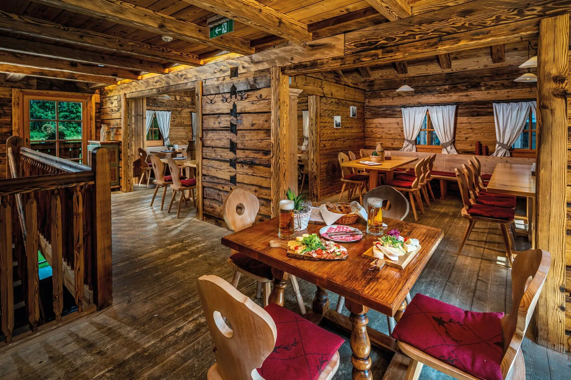 A dining room with tables and chairs and a table with food.