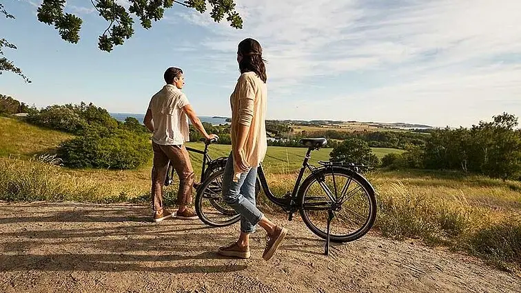 A man and a woman are standing next to bicycles outside.