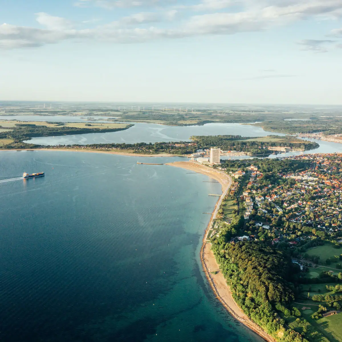 Travemünde from above Aerial view of a coastal town with a view of a large expanse of water and a cloudy sky.