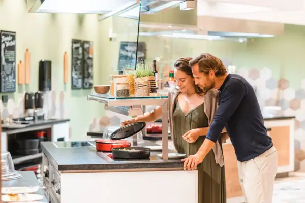 Buffet A man and a woman are standing next to a cooker.