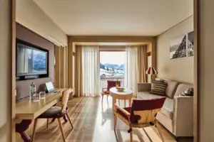 Suite living area A room with a table, chairs and a television.