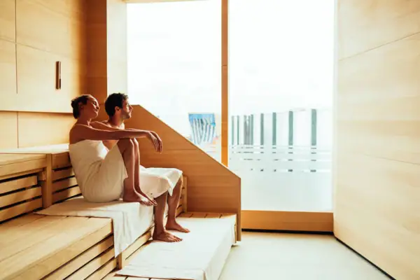 Panoramic sauna A man and a woman are sitting on a bench in a sauna.