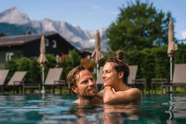A man and a woman in a pool, smiling.