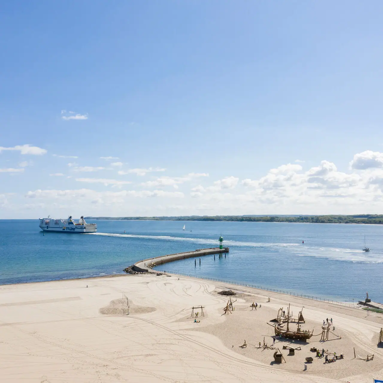 Travemünde resort beach A beach with a jetty and a boat in the water.