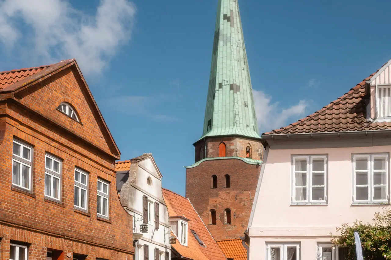 People walking on a street with buildings and a high tower.
