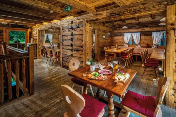 A dining room with tables and chairs and a table with food.